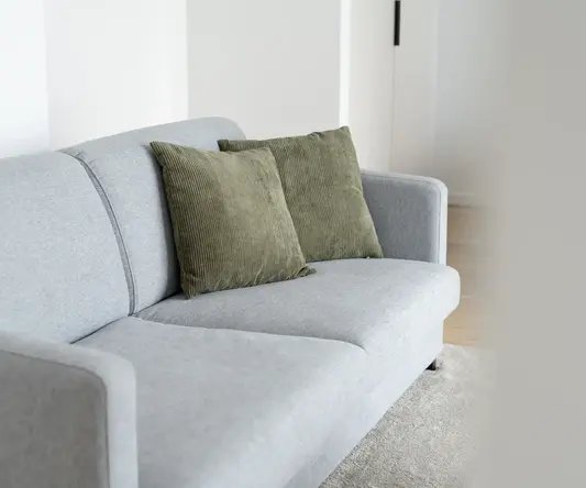a grey couch with green pillows