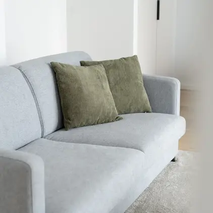a grey couch with green pillows