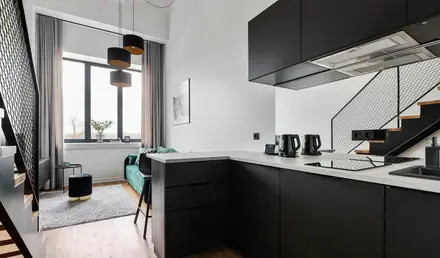 a kitchen with black cabinets and a green couch
