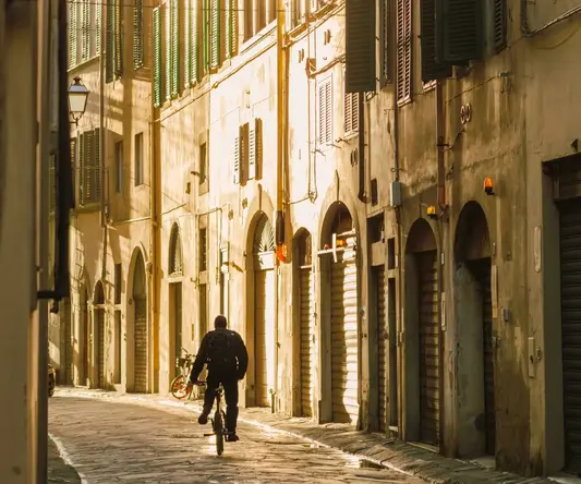 a person on a bicycle in a narrow alley between buildings