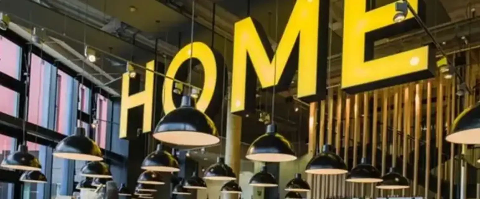 a yellow sign with black lights from the ceiling