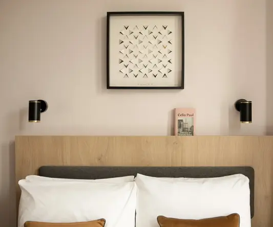 a bed with pillows and a picture on the wall