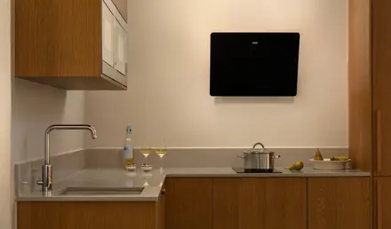 a kitchen with a stove and a pan and wine glasses