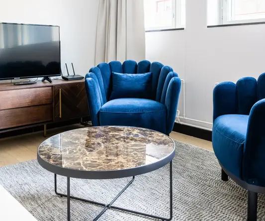 a living room with blue chairs and a television