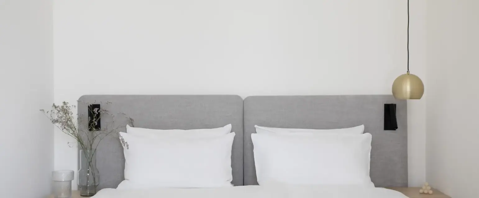 a bed with white sheets and a lamp