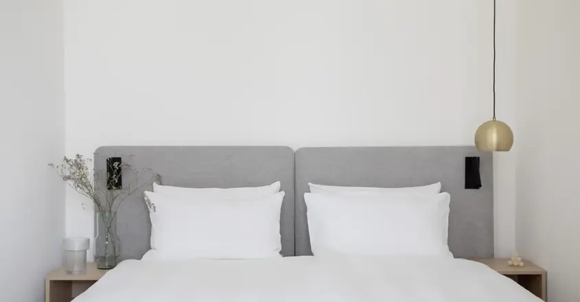 a bed with white sheets and a lamp
