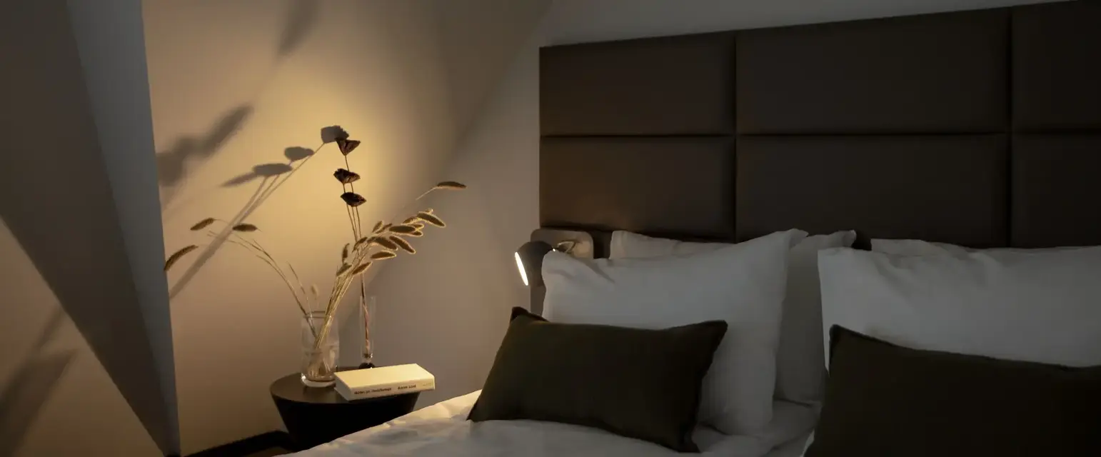 a bed with pillows and a vase of flowers