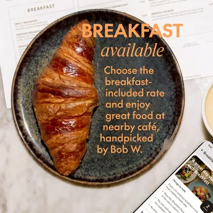 a croissant on a plate next to a phone and a cup of coffee