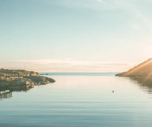 a body of water with rocks and a hill in the background