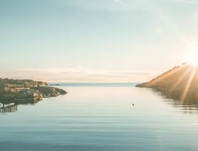 a body of water with rocks and a hill in the background