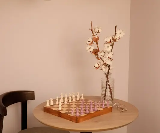 a chess board and a vase of cotton on a table