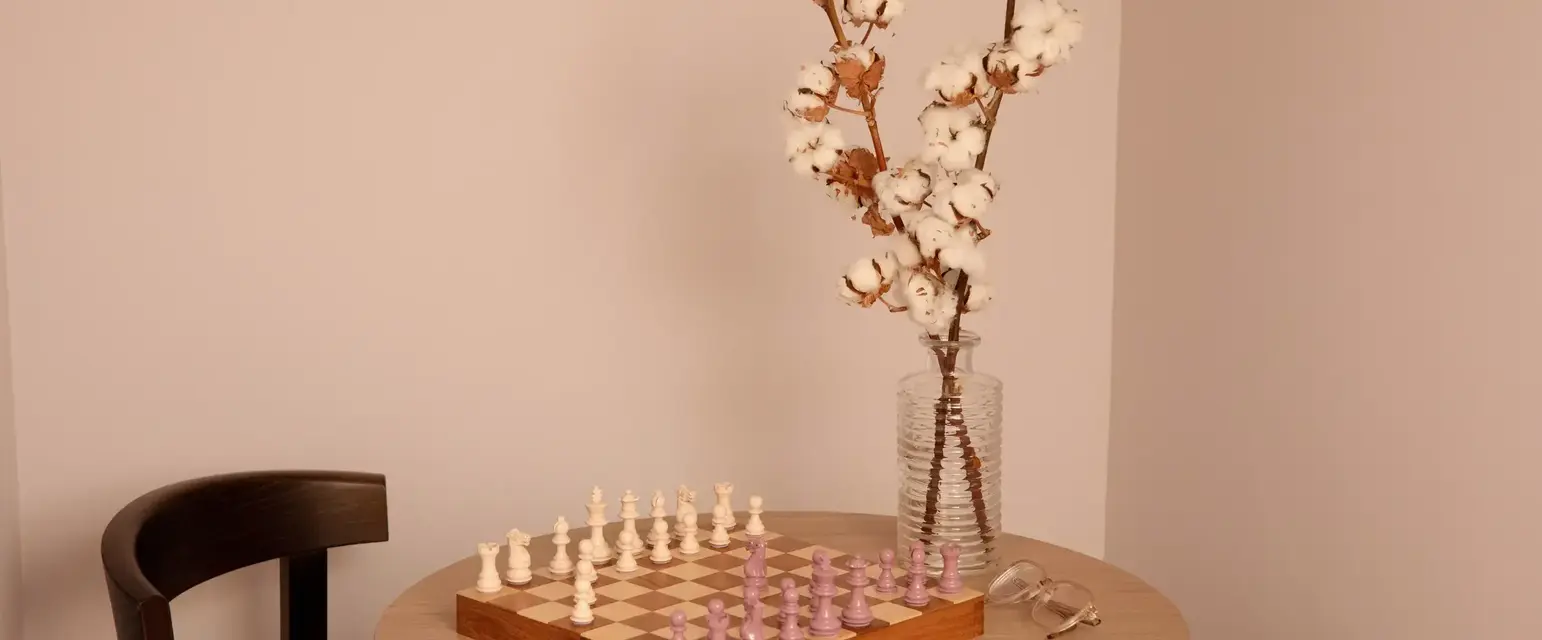 a chess board and a vase of cotton on a table