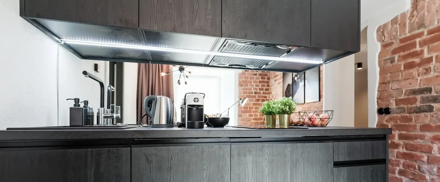 a kitchen with black cabinets and a brick wall