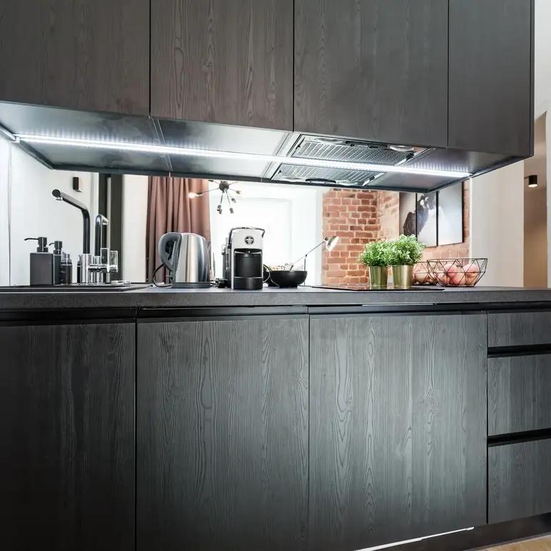 a kitchen with black cabinets and a brick wall