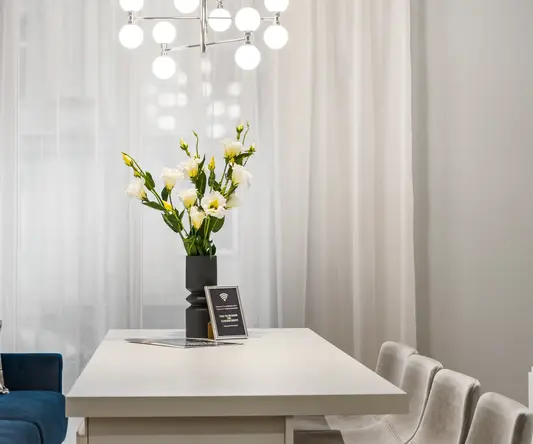 a white table with flowers and chairs in front of a chandelier