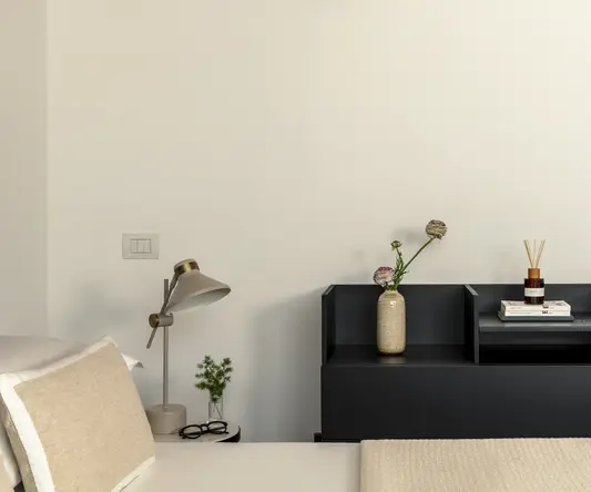 a bedroom with a black shelf and a white bed