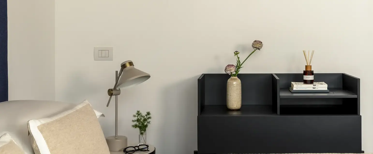 a bedroom with a black shelf and a white bed