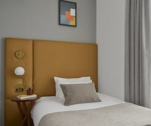 a bed with a brown headboard and a picture on the wall