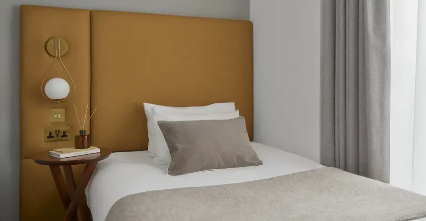 a bed with a brown headboard and a picture on the wall