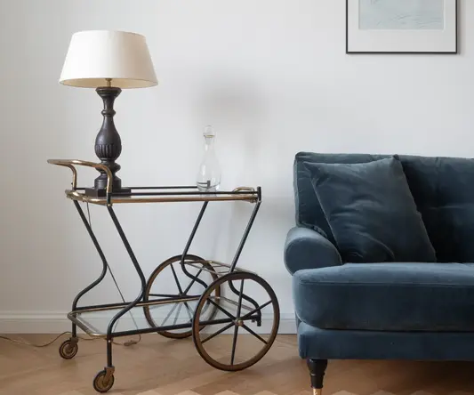 a blue couch with a lamp on a cart