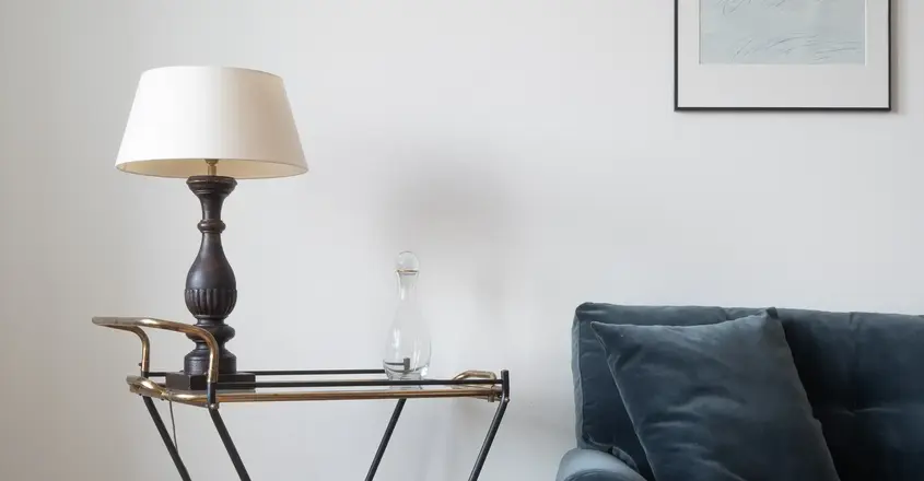 a blue couch with a lamp on a cart