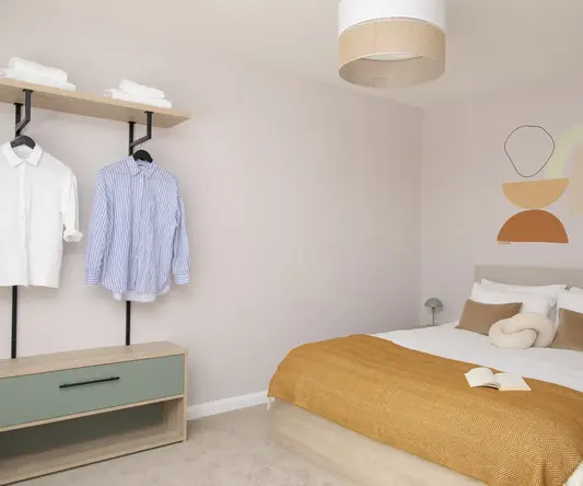 a room with a bed and a shelf with clothes on it