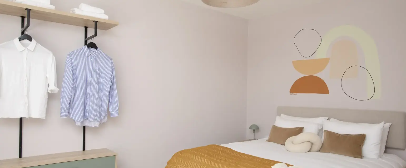 a room with a bed and a shelf with clothes on it