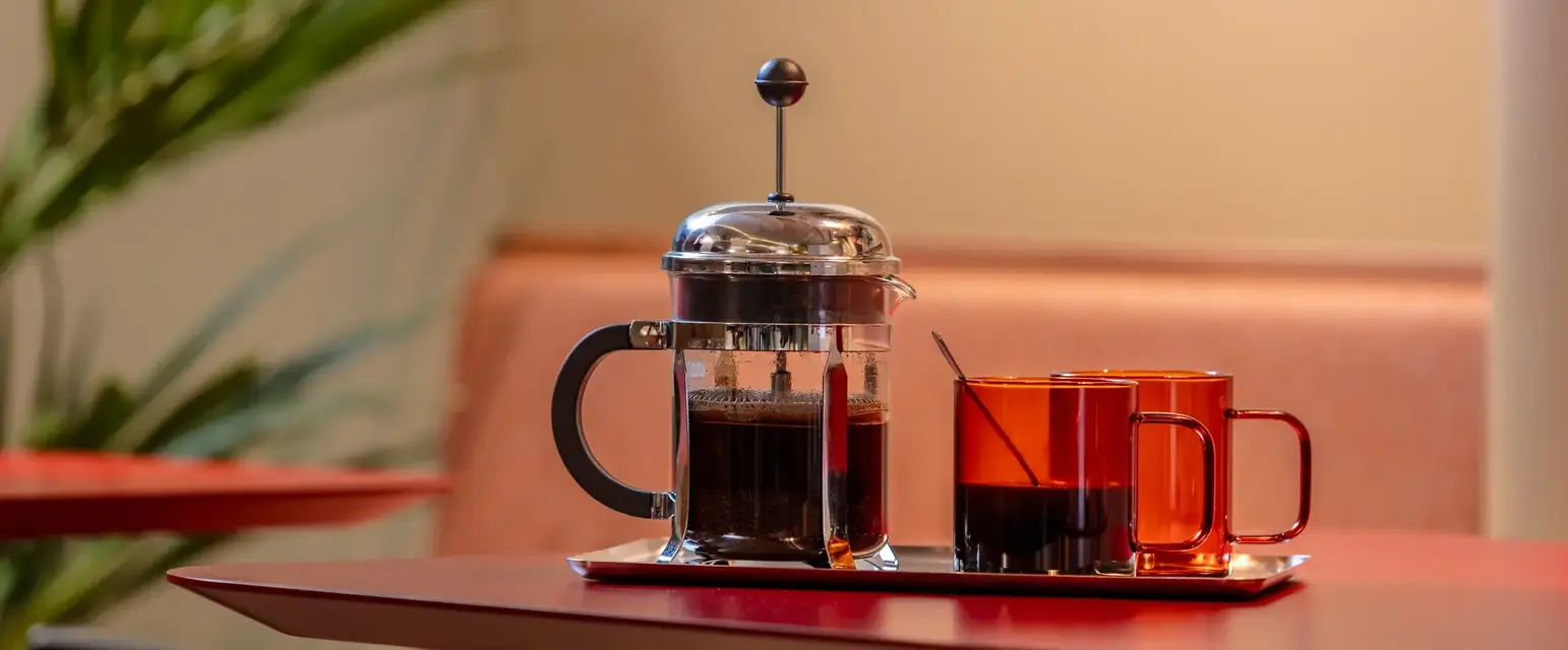 a coffee maker and two cups on a tray