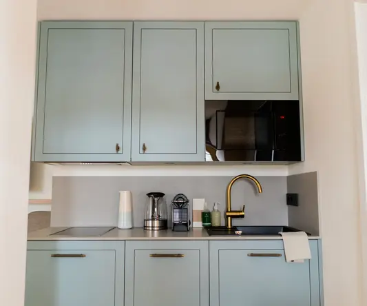 a kitchen with blue cabinets and a black microwave