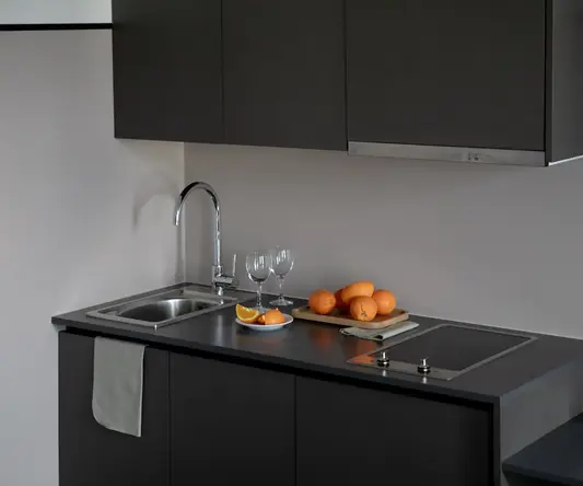 a kitchen counter with a sink and a tray of oranges