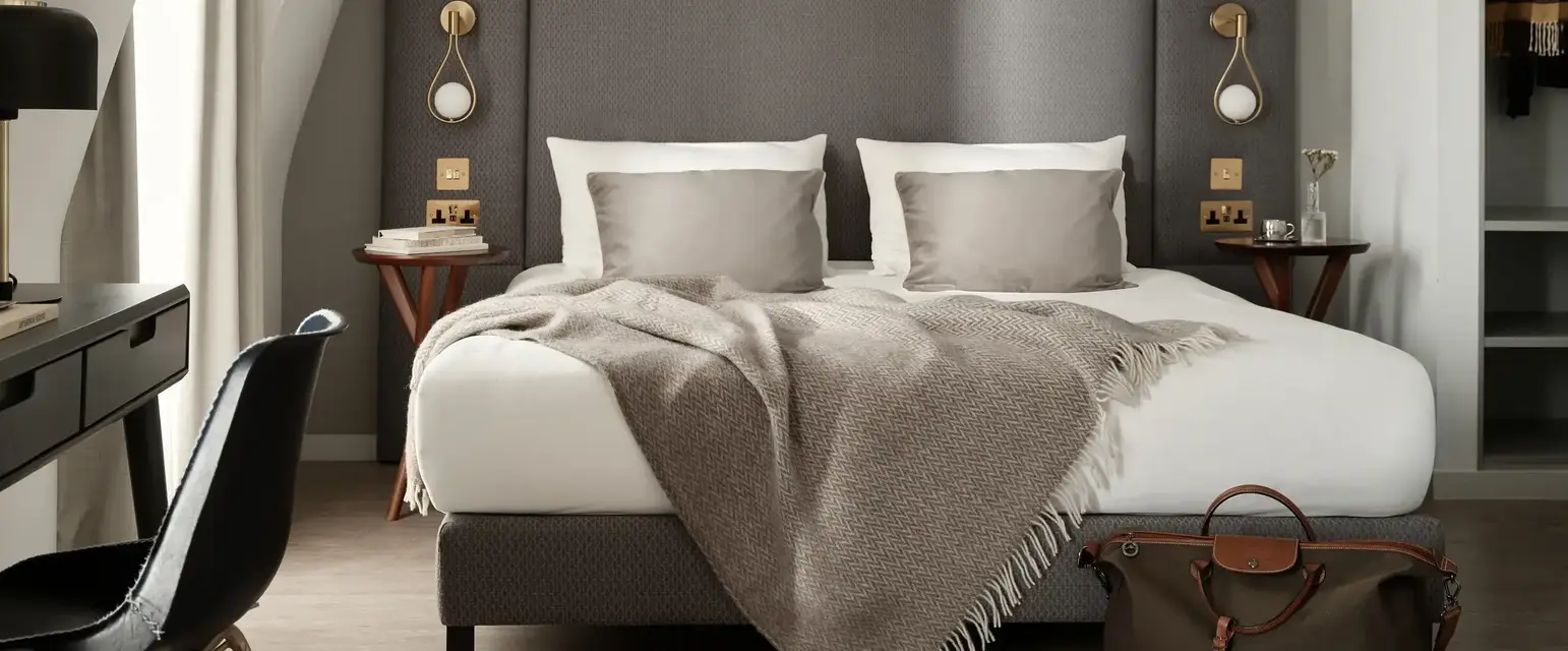 a bed with a blanket and a chair in a room