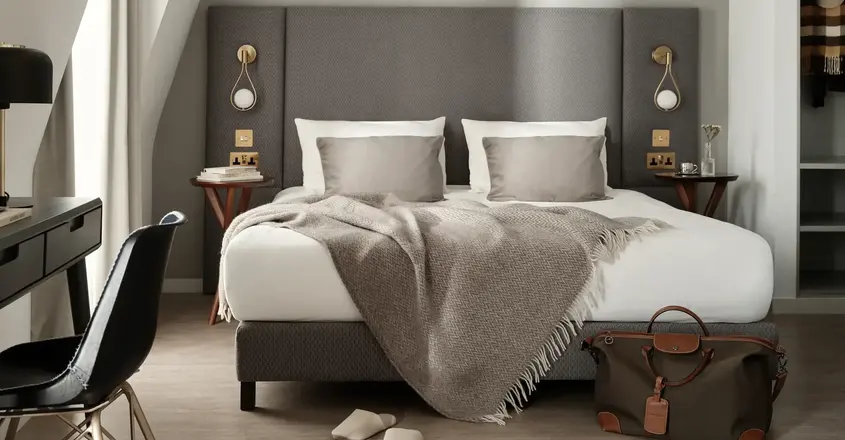 a bed with a blanket and a chair in a room