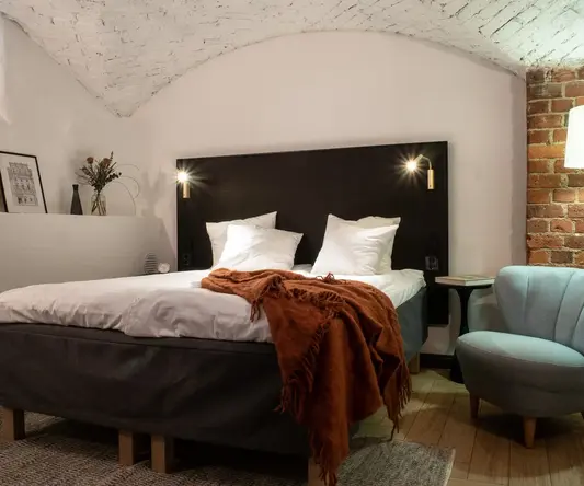 a bed with pillows and a chair in a room