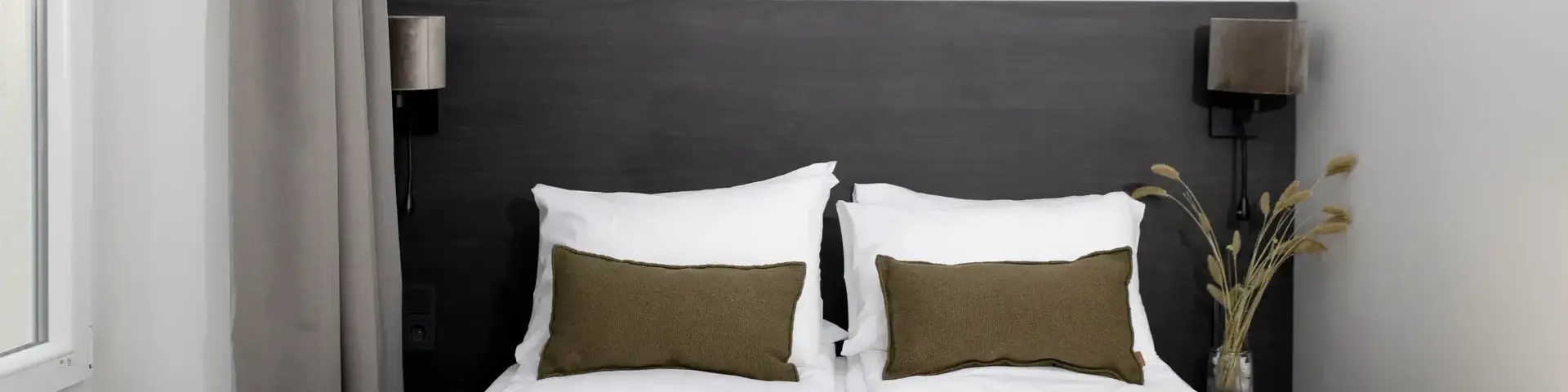 a bed with pillows and a vase of flowers