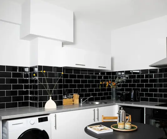 a kitchen with black tile walls and a black countertop