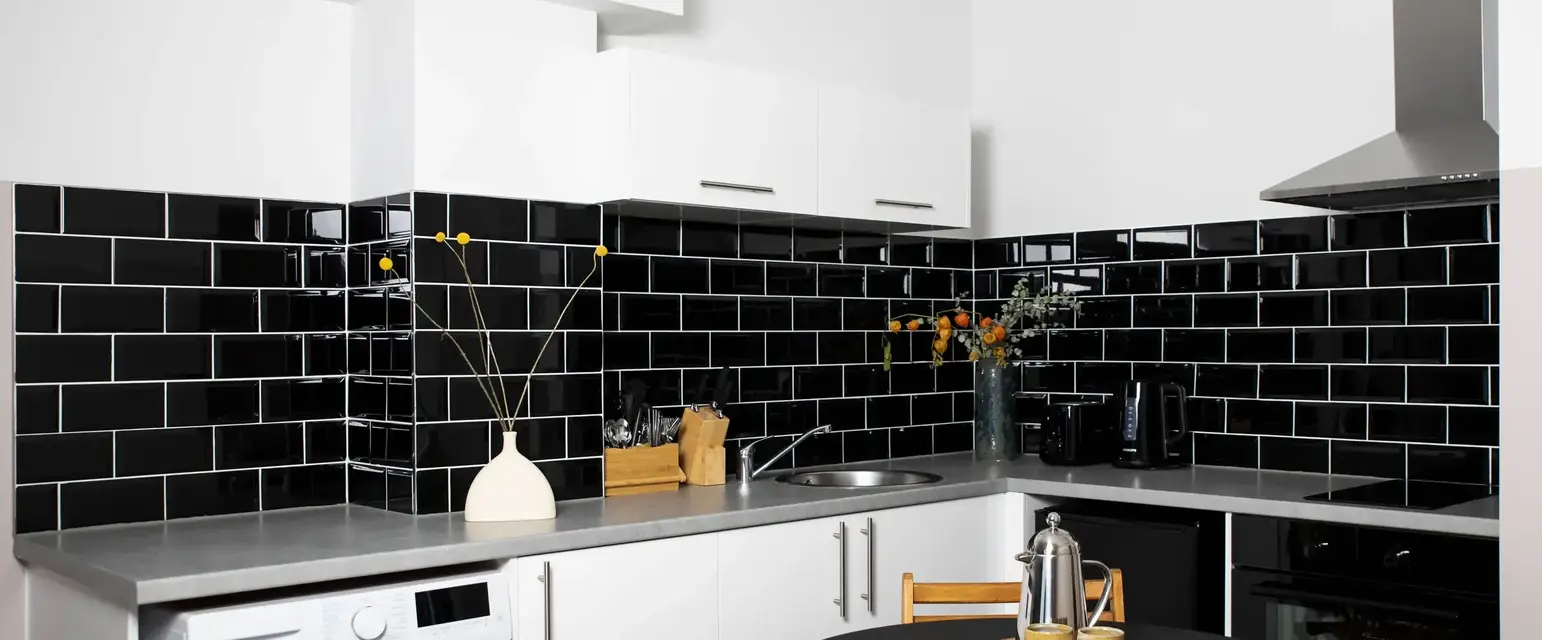 a kitchen with black tile walls and a black countertop