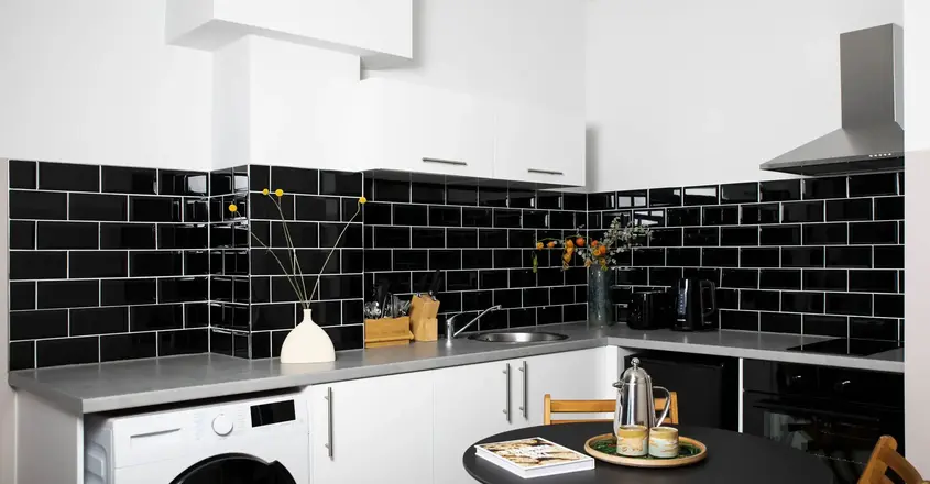 a kitchen with black tile walls and a black countertop