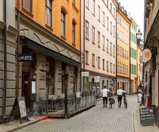 a group of people walking down a narrow street with buildings