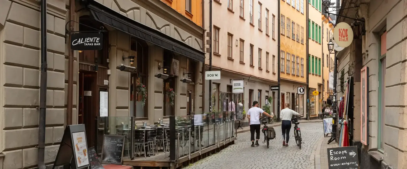 a group of people walking down a narrow street with buildings