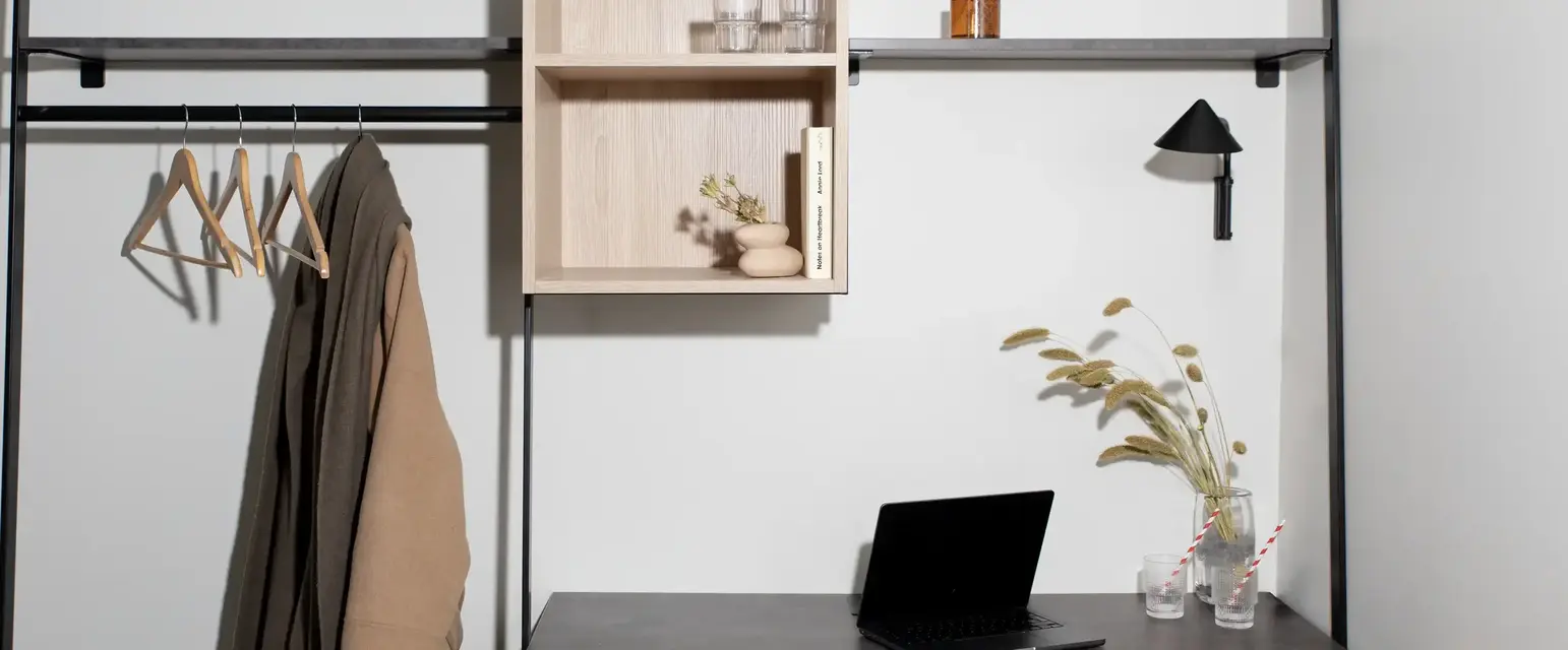 a desk with a laptop and shelves on it